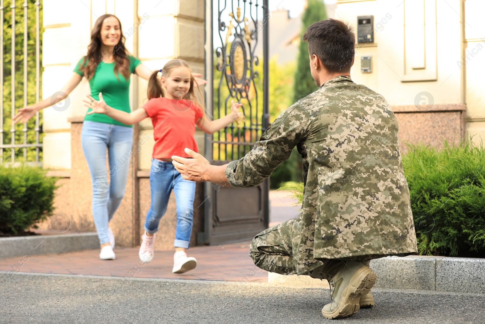 Photo of Happy family running to man in military uniform outdoors