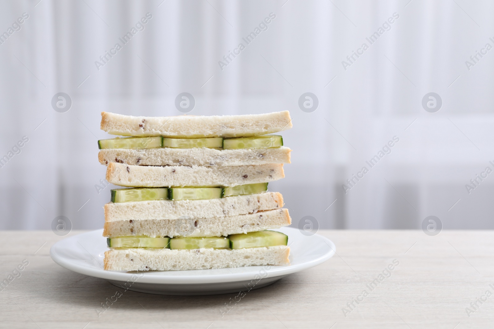 Photo of Tasty sandwiches with cream cheese and cucumber on white wooden table. Space for text