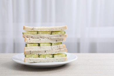 Photo of Tasty sandwiches with cream cheese and cucumber on white wooden table. Space for text