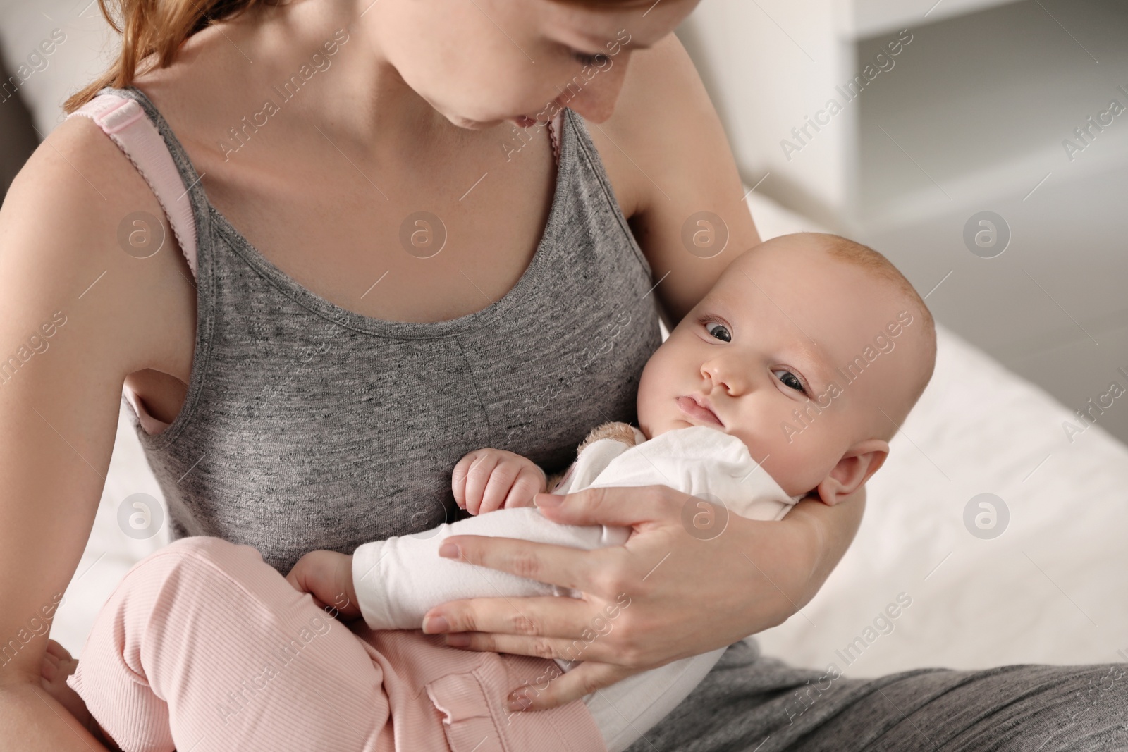 Photo of Young woman with her little baby resting after breast feeding on bed, closeup