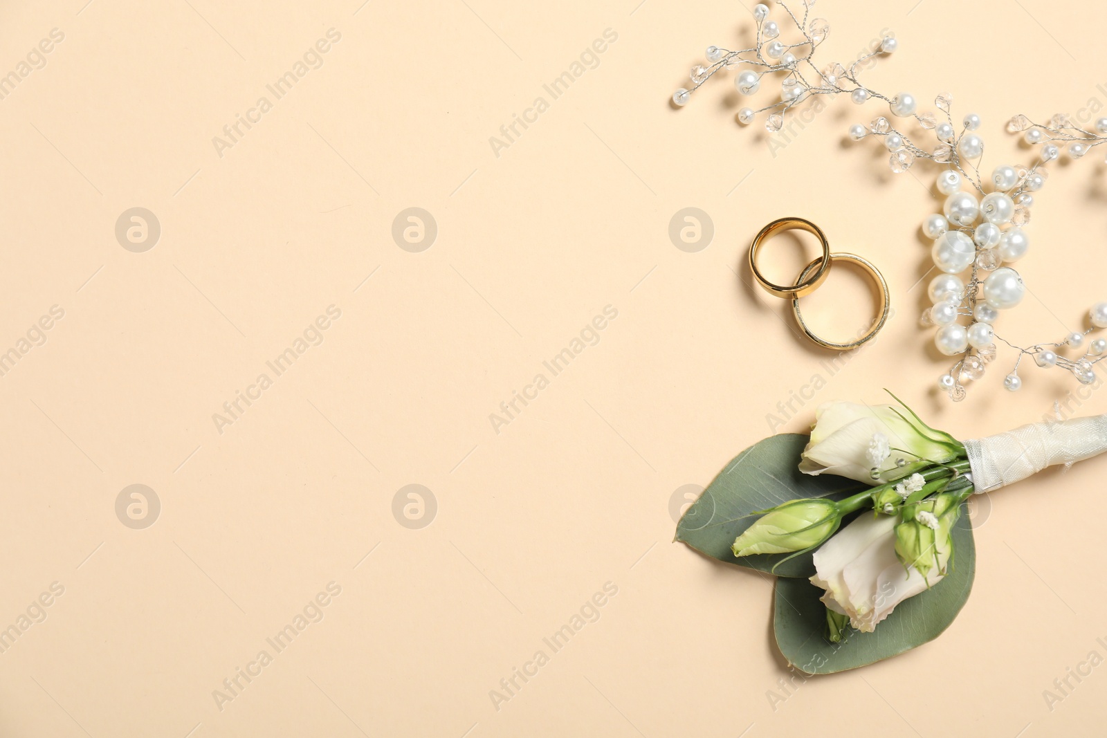 Photo of Wedding stuff. Stylish boutonniere, rings and decor on beige background, flat lay. Space for text