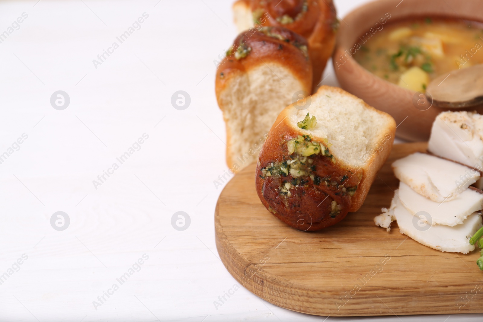 Photo of Delicious pampushky (buns with garlic) and salo served for borsch on white wooden table, space for text. Traditional Ukrainian cuisine