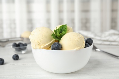 Photo of Delicious vanilla ice cream with blueberries served on wooden table