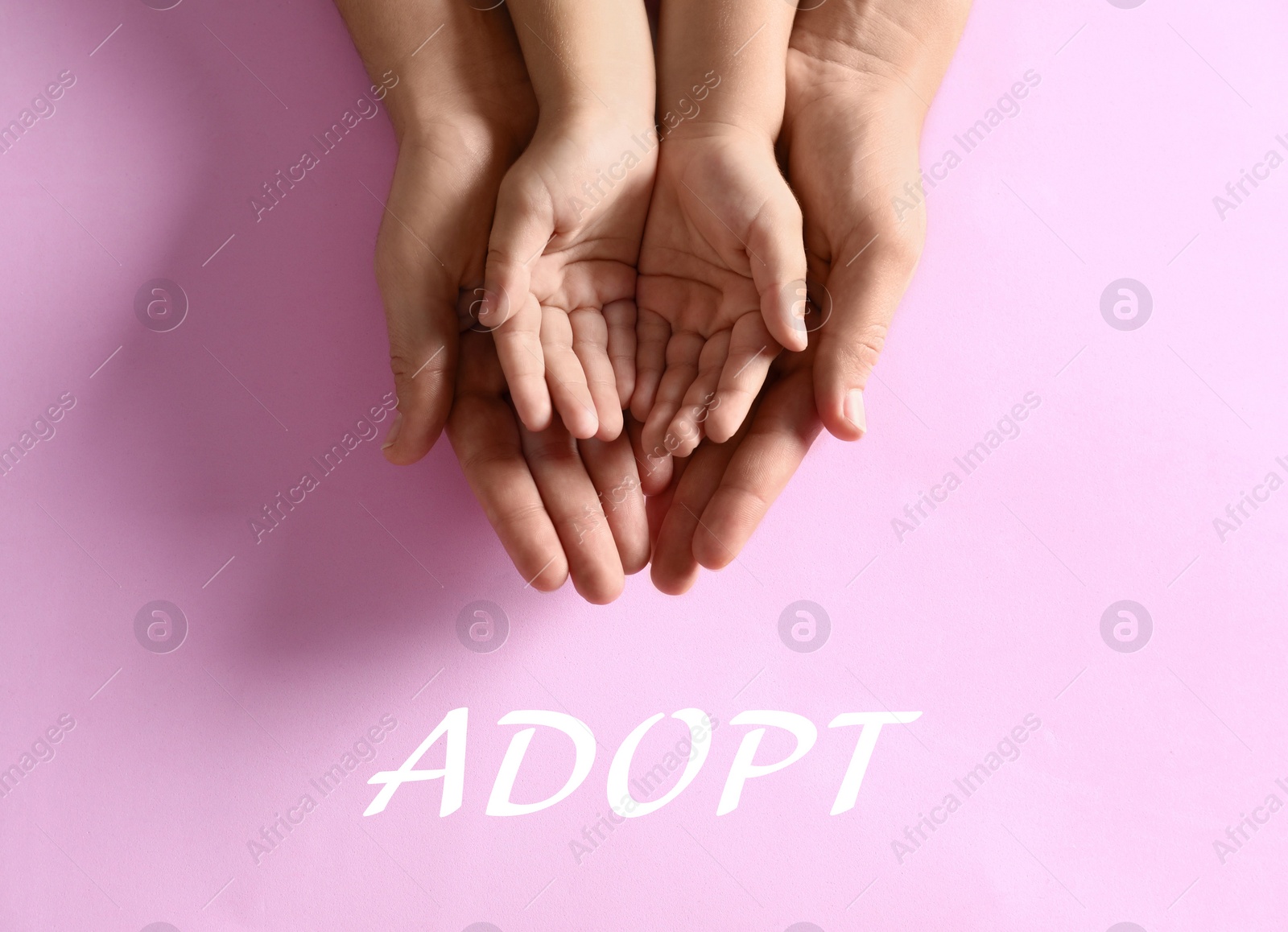 Image of Mother holding hands with her child on pink background, top view. Adoption concept