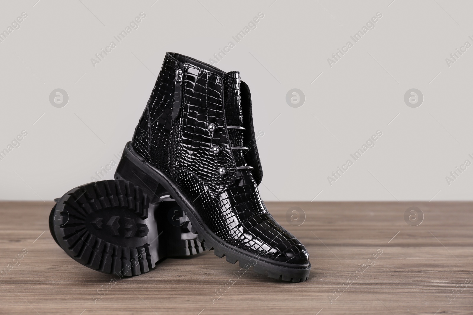 Photo of Pair of stylish ankle boots on wooden background. Space for text