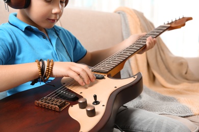 Photo of Little boy playing guitar on sofa, closeup