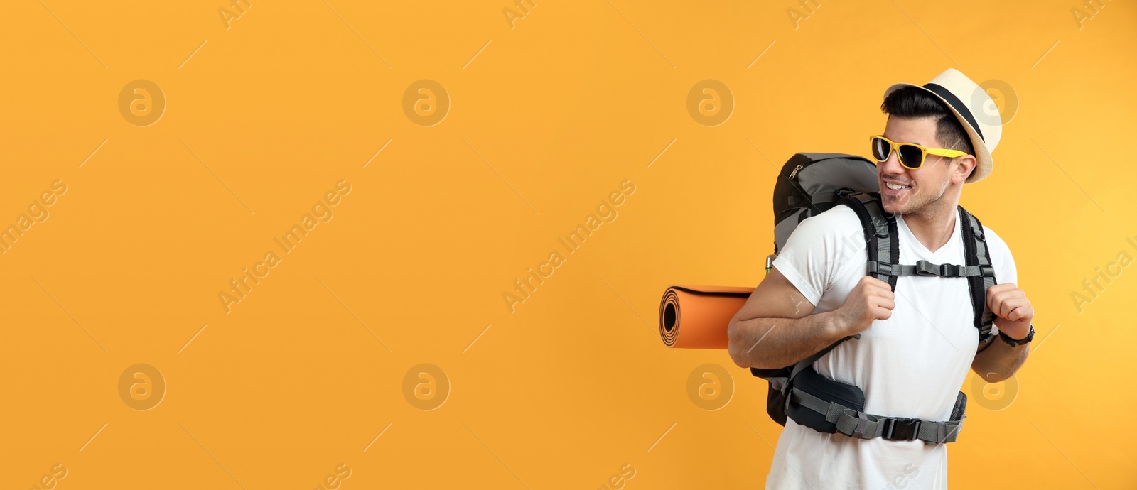 Photo of Male tourist with travel backpack on yellow background, space for text