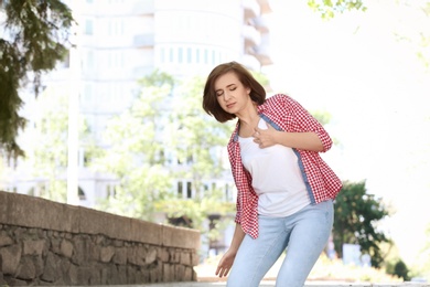 Mature woman having heart attack, outdoors