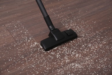 Photo of Vacuuming scattered rice from wooden floor in room