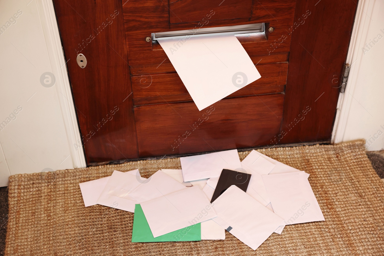 Photo of Wooden door with mail slot and many envelopes indoors