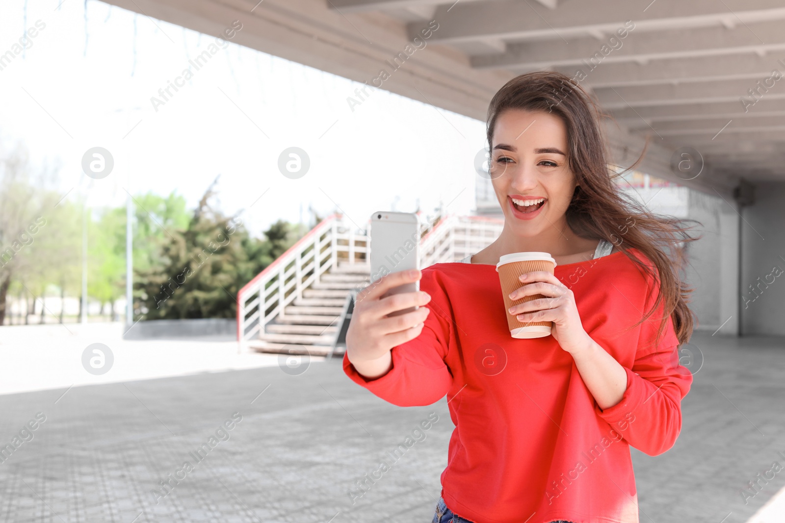 Photo of Attractive young woman taking selfie with phone outdoors