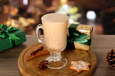 Image of Glass of delicious eggnog, spices, cookie and gift boxes on wooden table in bar