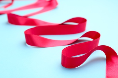 Photo of Simple pink ribbon on color background, closeup