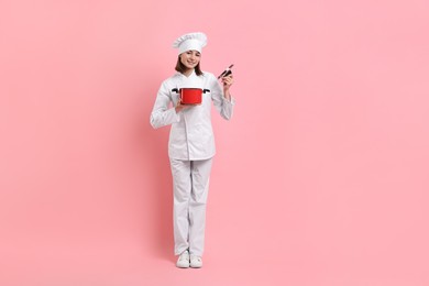 Photo of Professional chef with cooking pot on pink background