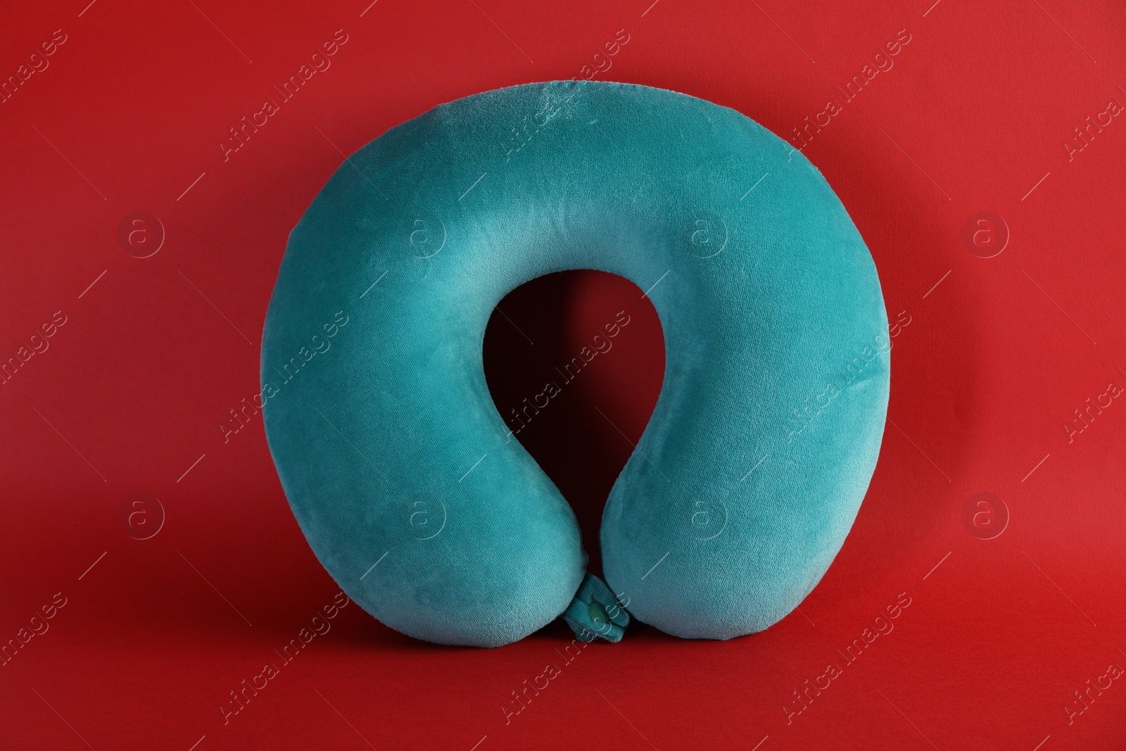 Photo of One turquoise travel pillow on red background