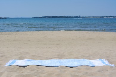 Photo of Light blue towel on sandy beach near sea, space for text