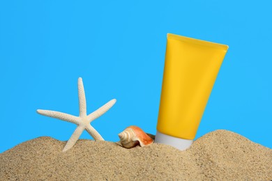Sand with sunscreen, seashell and starfish against blue background, space for text. Sun protection care