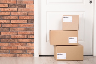 Photo of Cardboard parcel boxes on floor near apartment entrance. Mockup for design