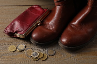 Poverty. Old boots, wallet and coins on wooden table