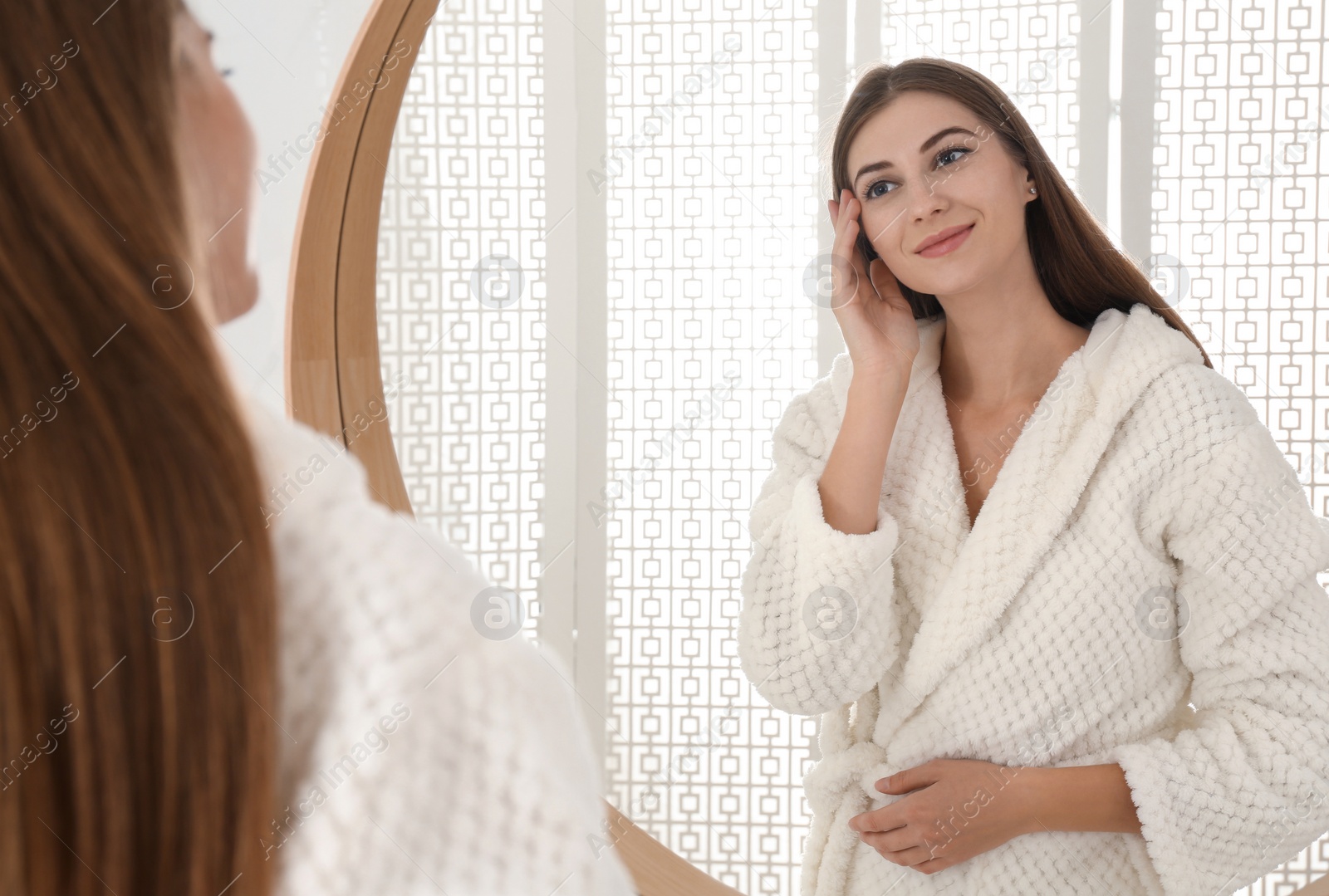 Photo of Young woman near mirror in bathroom. Skin care