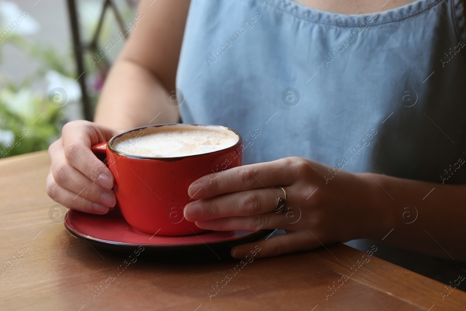 Photo of Woman with cup of fresh aromatic coffee at table, closeup