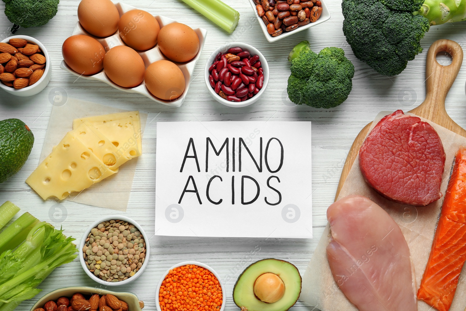 Photo of Different fresh products and paper with words Amino Acids on white wooden table, flat lay