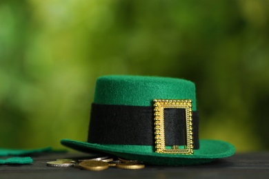 Photo of Leprechaun hat and coins on wooden table against blurred background, space for text. St Patrick's Day celebration