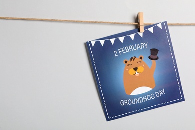 Happy Groundhog Day greeting card hanging on light background, space for text