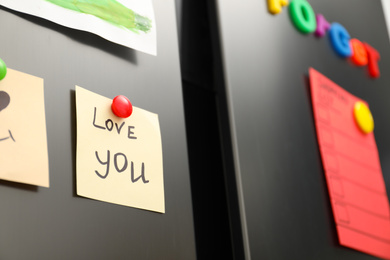 Photo of Note with phrase LOVE YOU and magnets on refrigerator, closeup