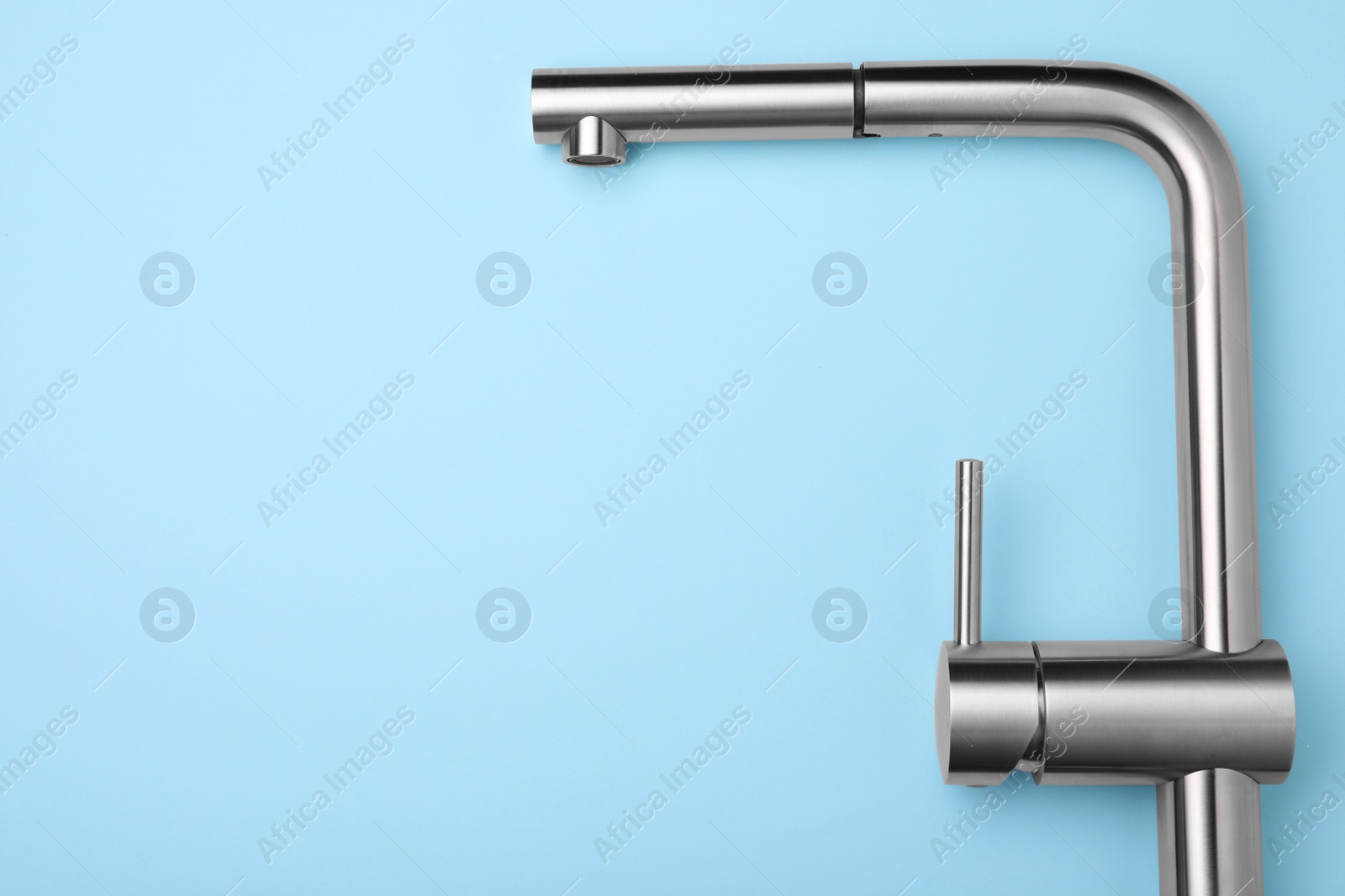 Photo of Modern pull out kitchen faucet on light blue background, top view. Space for text