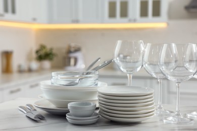 Photo of Different clean dishware, cutlery and glasses on white marble table in kitchen