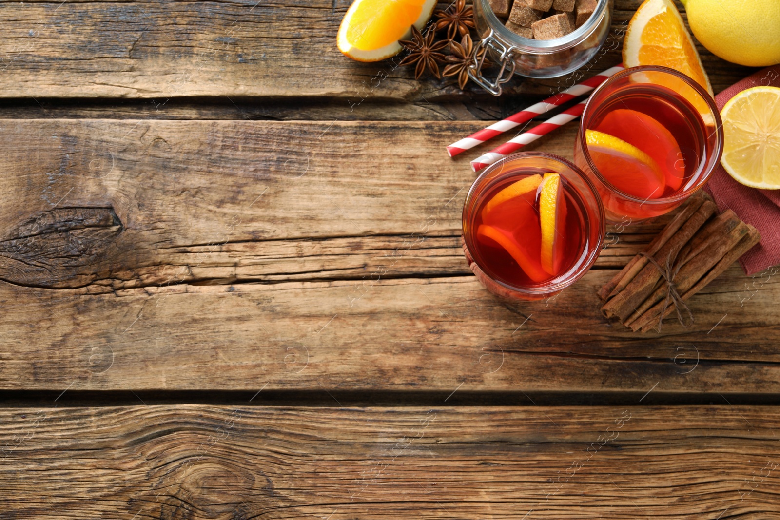 Photo of Aromatic punch drink and ingredients on wooden table, flat lay. Space for text