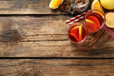 Photo of Aromatic punch drink and ingredients on wooden table, flat lay. Space for text