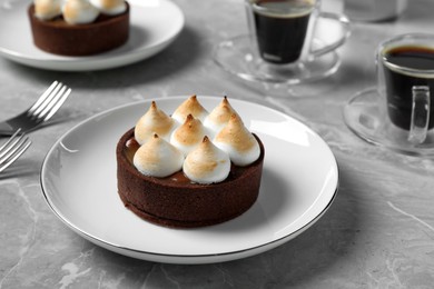 Photo of Delicious salted caramel chocolate tart with meringue served on light grey marble table, closeup