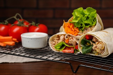Photo of Delicious tortilla wraps with tuna on wooden table, space for text
