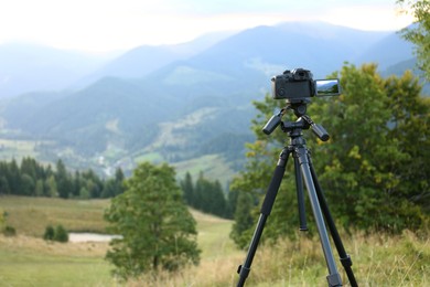 Photo of Taking video with modern camera on tripod in mountains