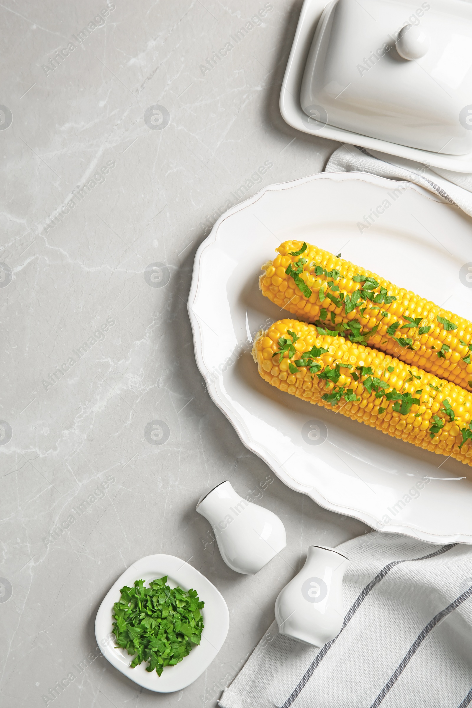 Photo of Plate with delicious boiled corn cobs and parsley on light table, top view