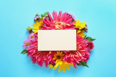 Flat lay composition with beautiful dahlia flowers and blank card on color background