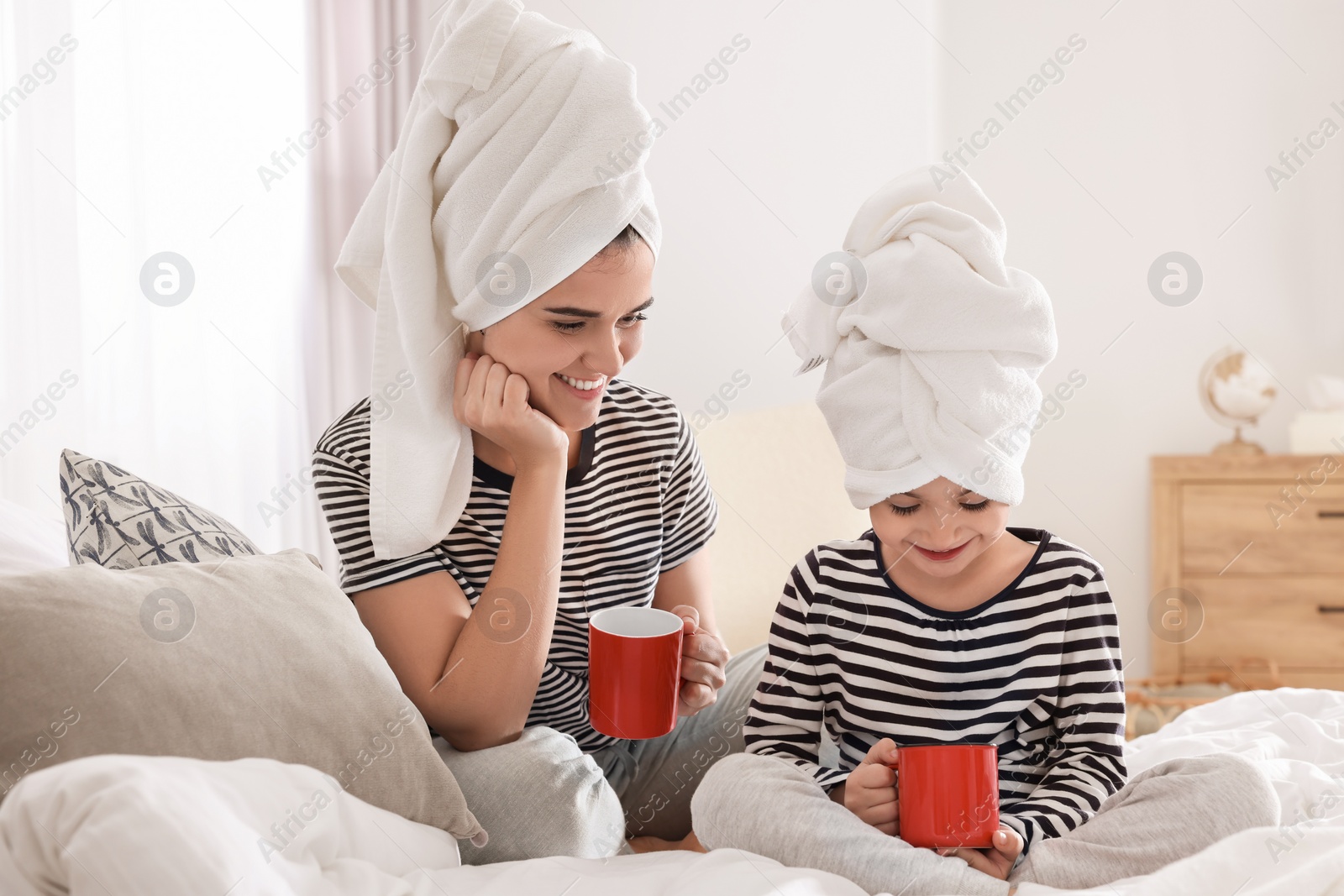 Photo of Young mother and her daughter spending time together on bed at home