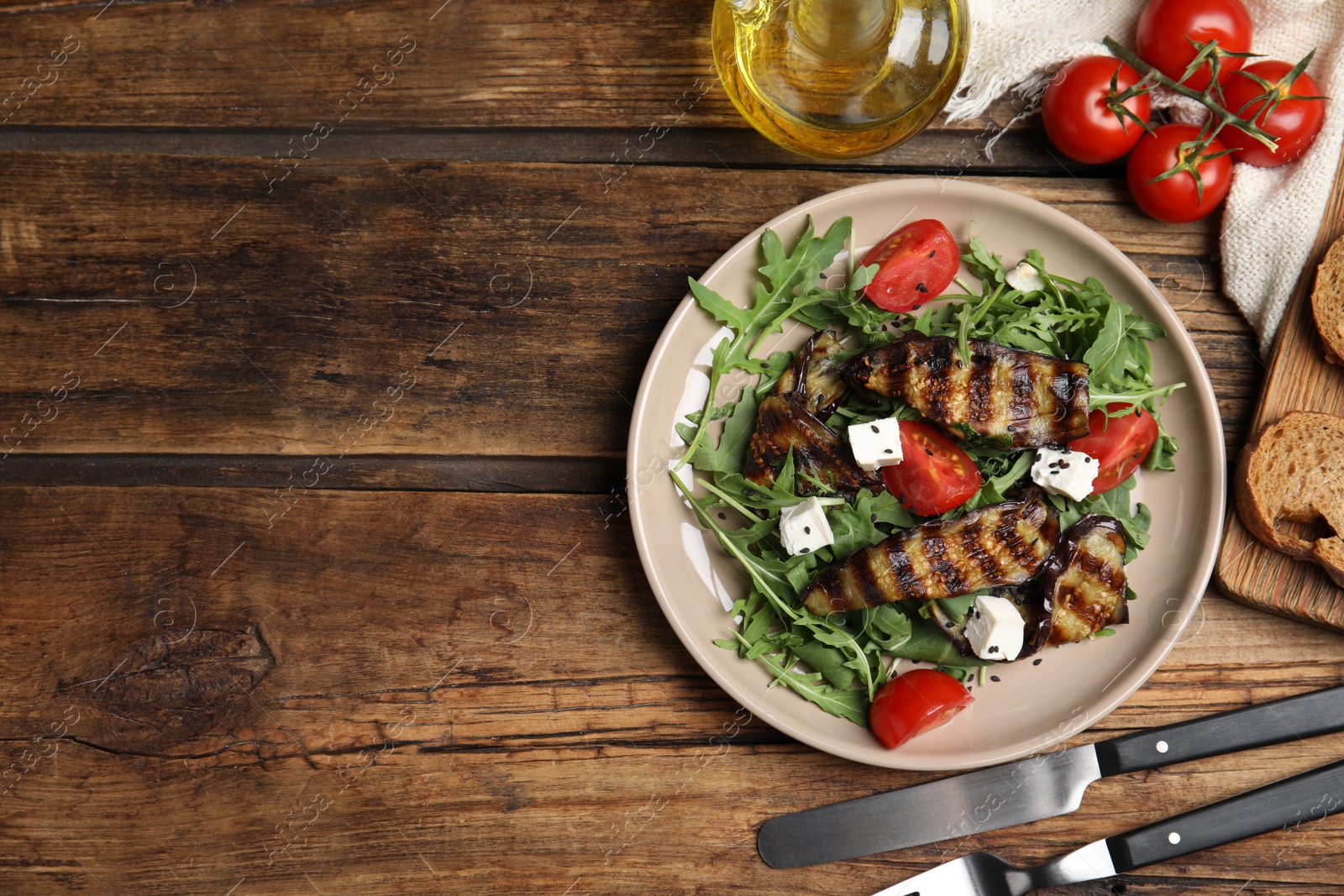 Photo of Delicious salad with roasted eggplant, feta cheese and arugula served on wooden table, flat lay. Space for text