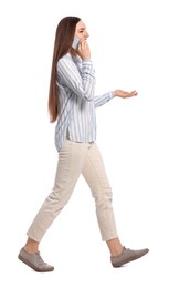 Young woman in casual outfit talking on smartphone while walking against white background