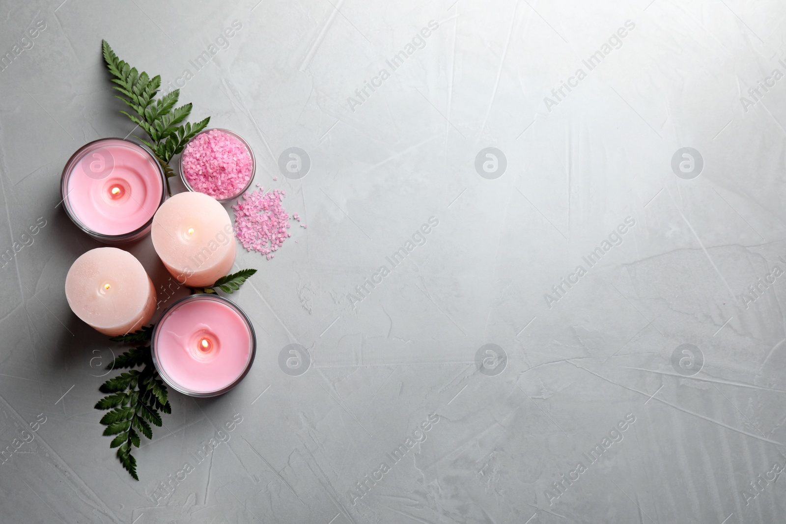 Photo of Candles, fern leaves and sea salt on light grey stone table, flat lay. Space for text