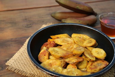 Tasty deep fried banana slices on wooden table