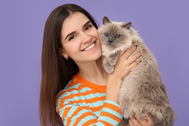 Happy woman with her cute cat on violet background