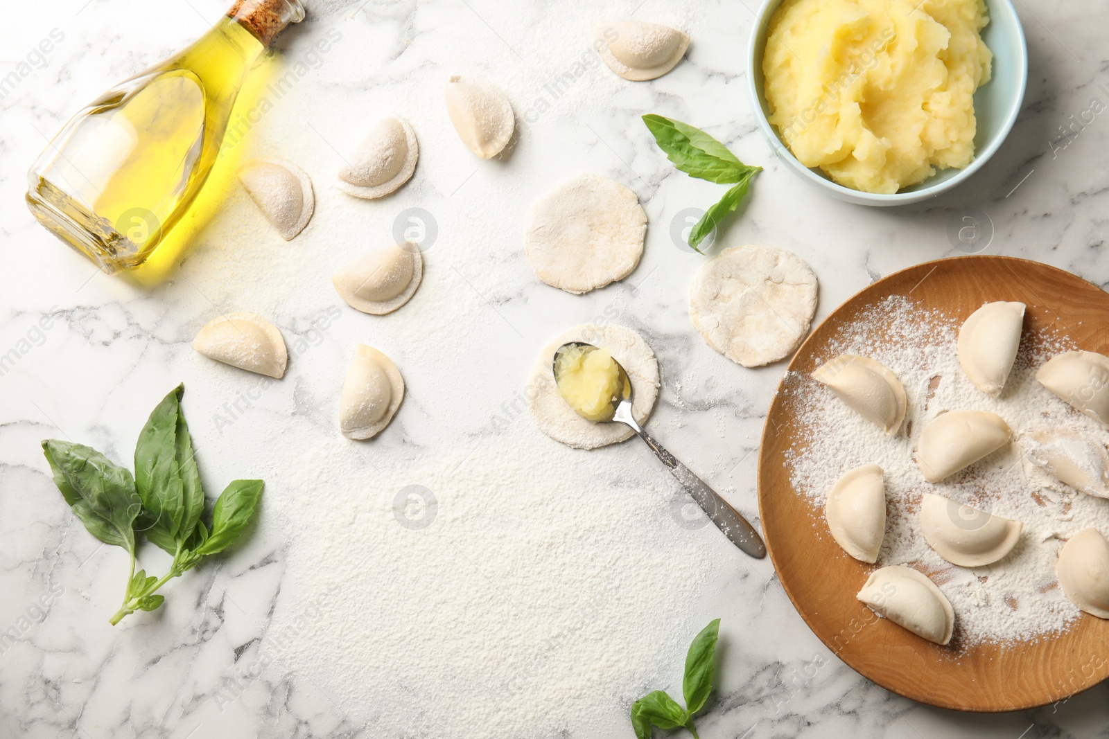 Photo of Flat lay composition with raw dumplings, oil and mashed potatoes on marble background. Process of cooking