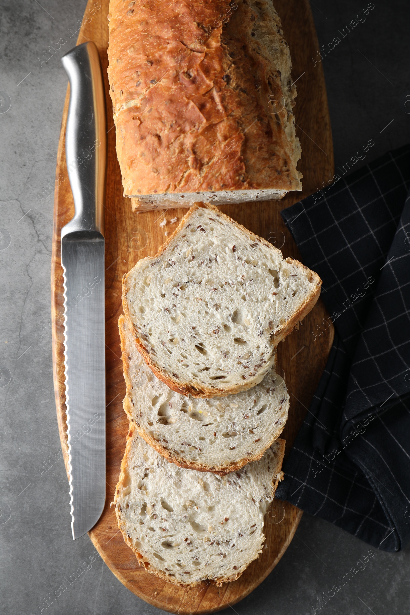 Photo of Freshly baked cut sourdough bread and knife on grey table, top view