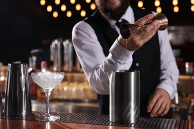 Bartender preparing fresh alcoholic cocktail at bar counter, closeup