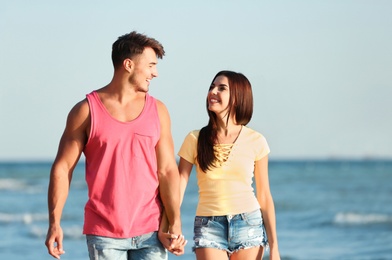 Photo of Happy young couple walking together on beach