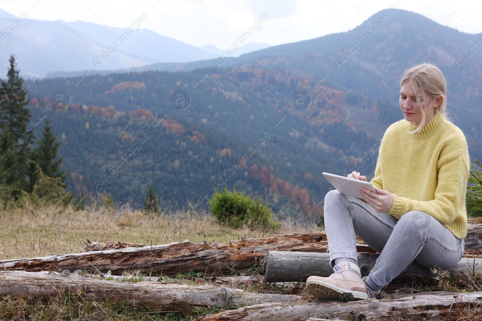 Photo of Young woman drawing with graphic tablet in mountains