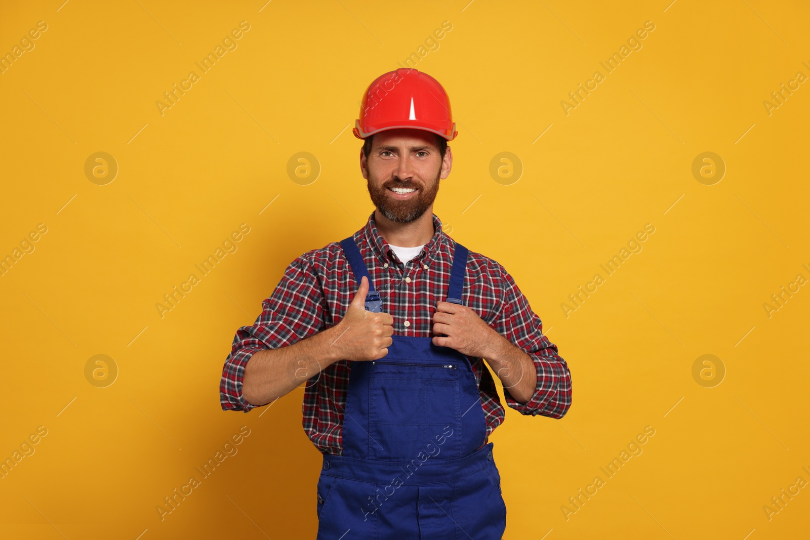 Photo of Professional builder in uniform on yellow background